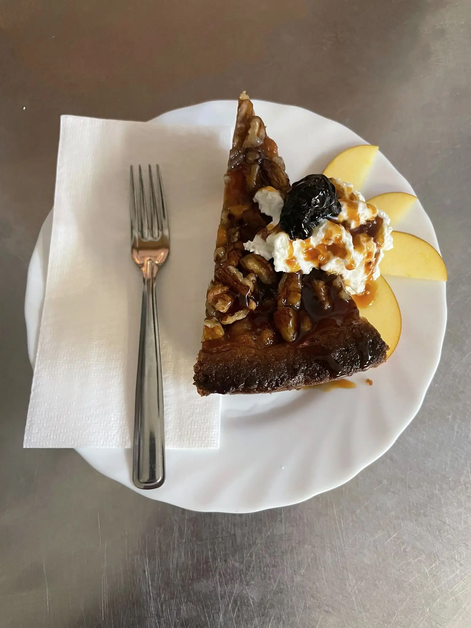 Ein Stück Kuchen mit Nüssen, Sahne und Apfelspalten