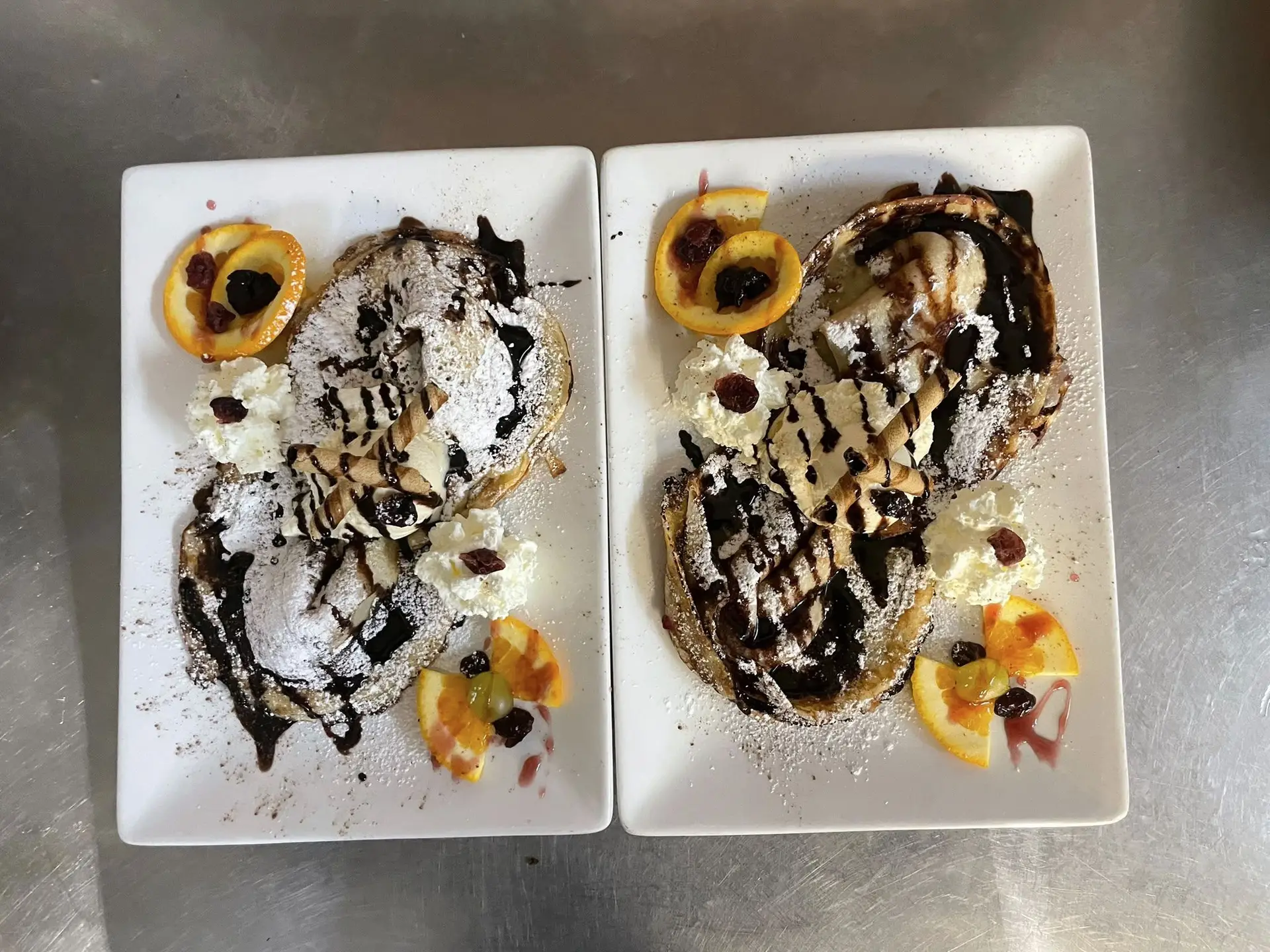 Zwei Teller mit Palatschinken, Schokosauce, Sahne und Orangenscheiben